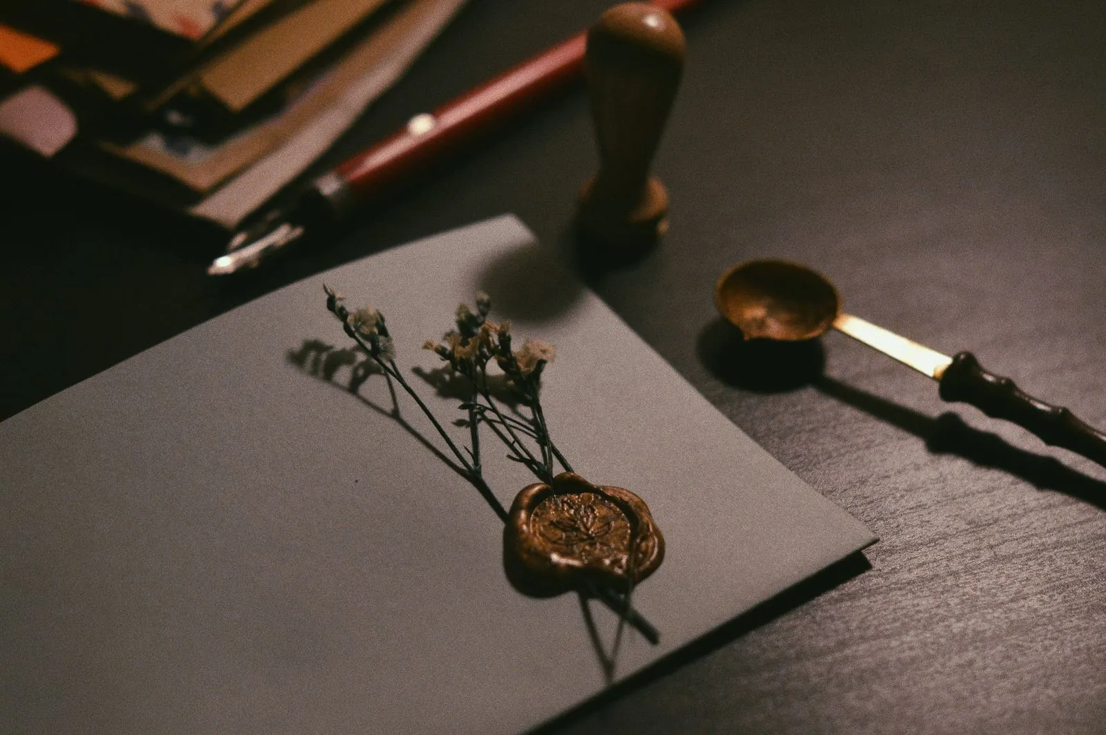 A sealed envelope with a wax seal and a stamp on a dark desk