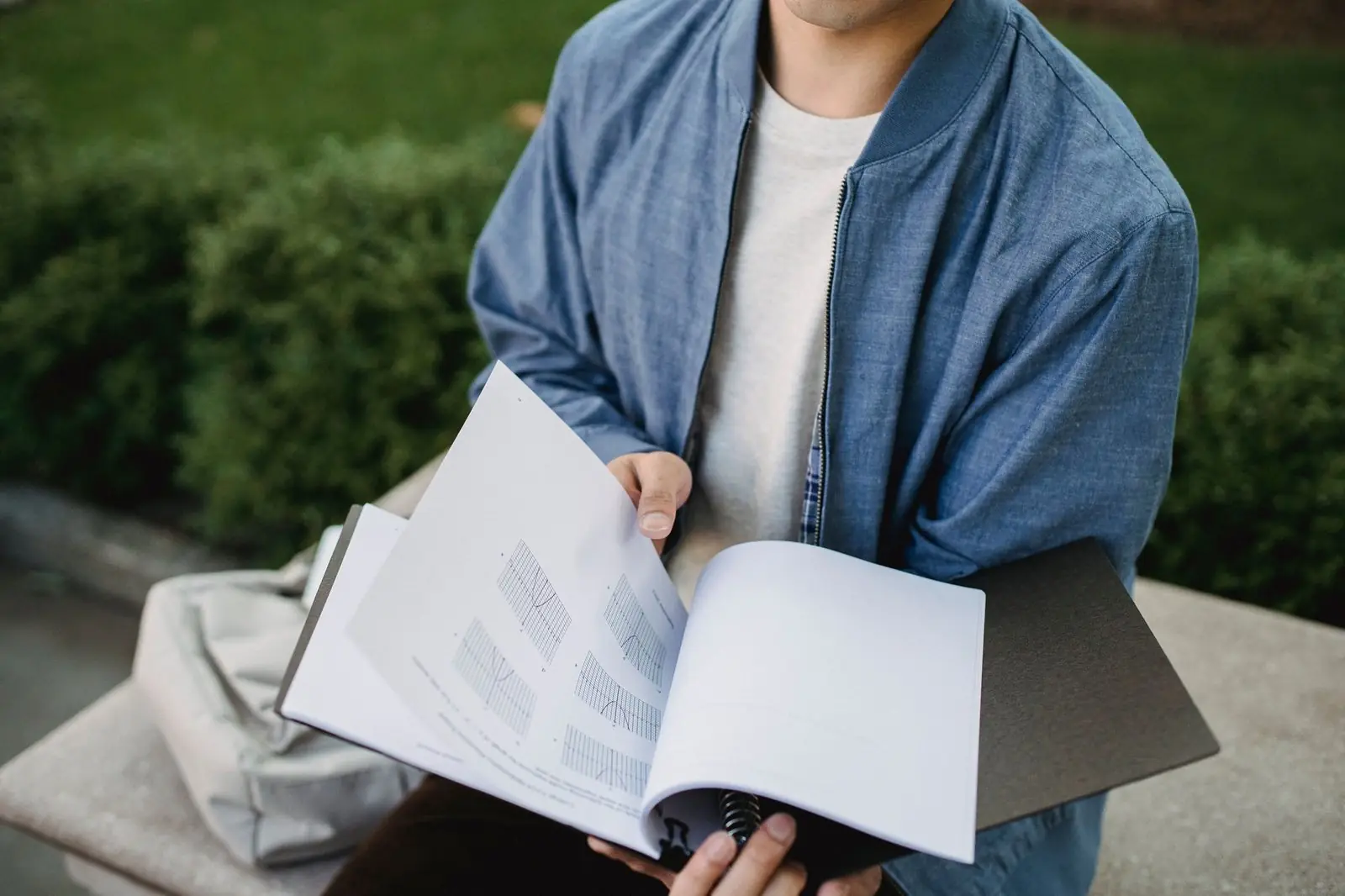 A man in a denim jacket reading through a printed document