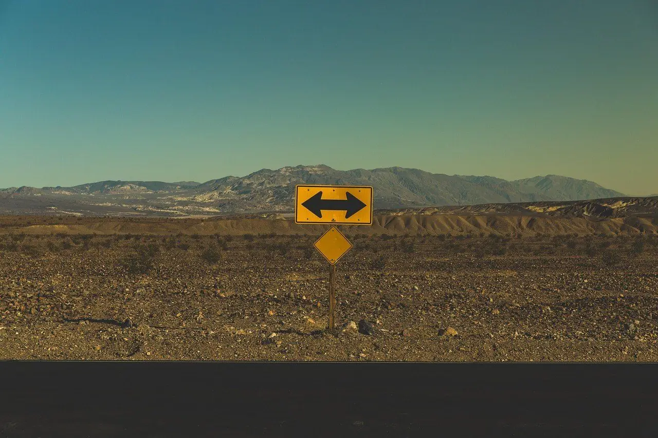 Road sign with arrows pointing two ways in open country