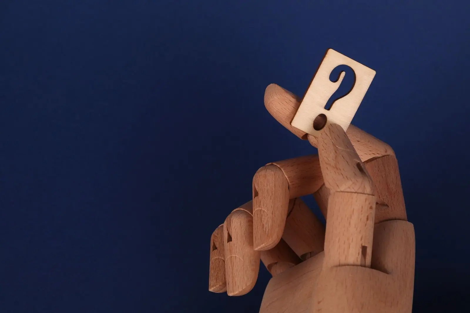 Wooden hand holding a card with a question mark