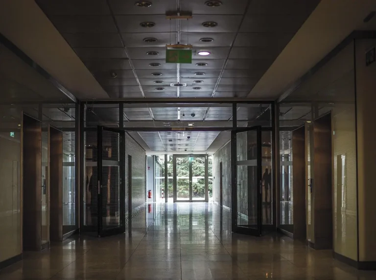 A long office corridor with glass doors and lifts on both sides