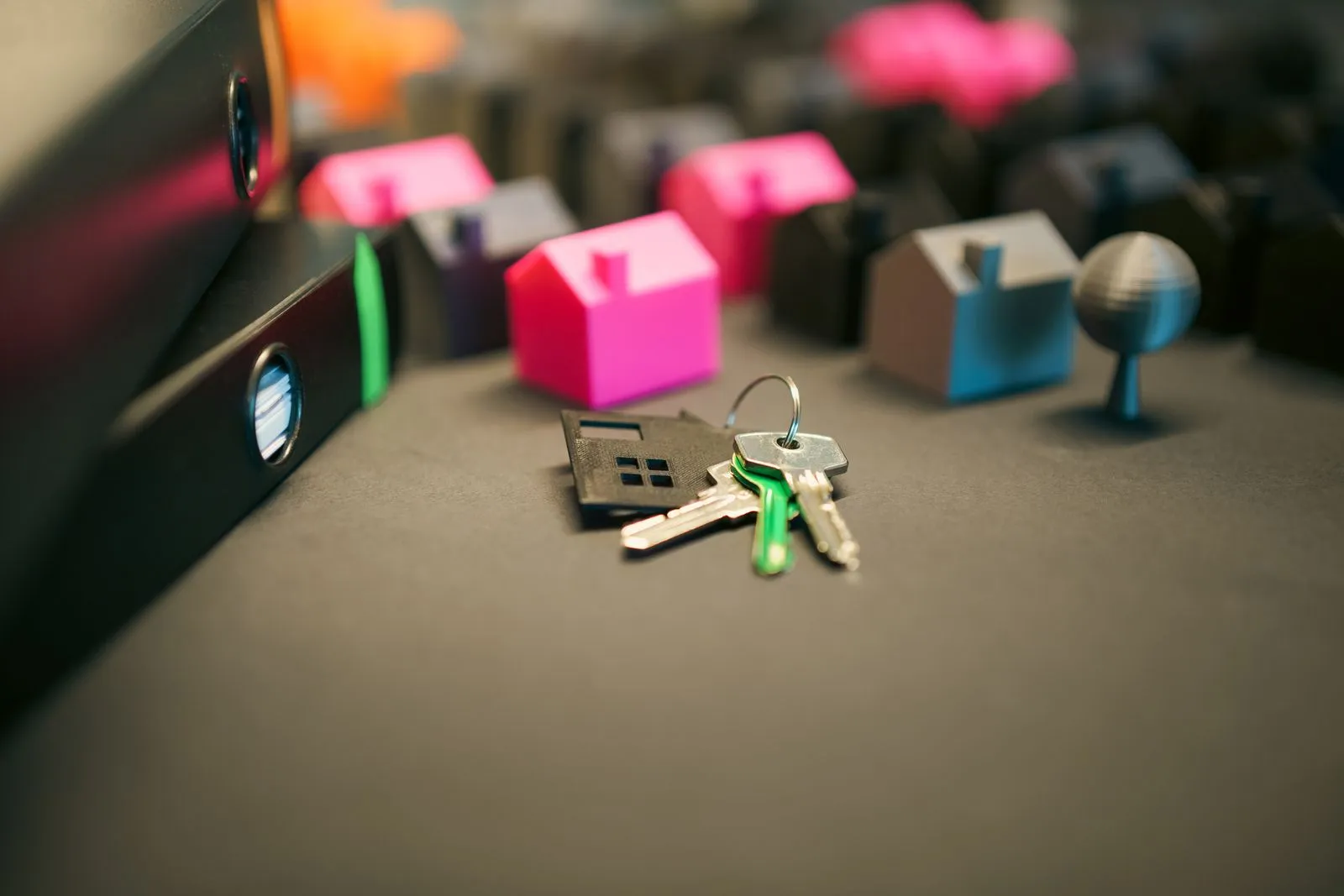 House keys lying beside small model houses on a dark table