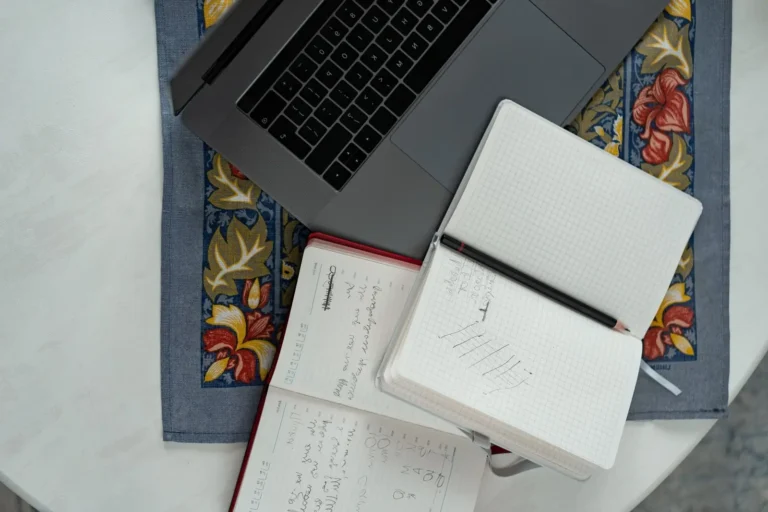 Open notebooks with handwritten notes beside a laptop