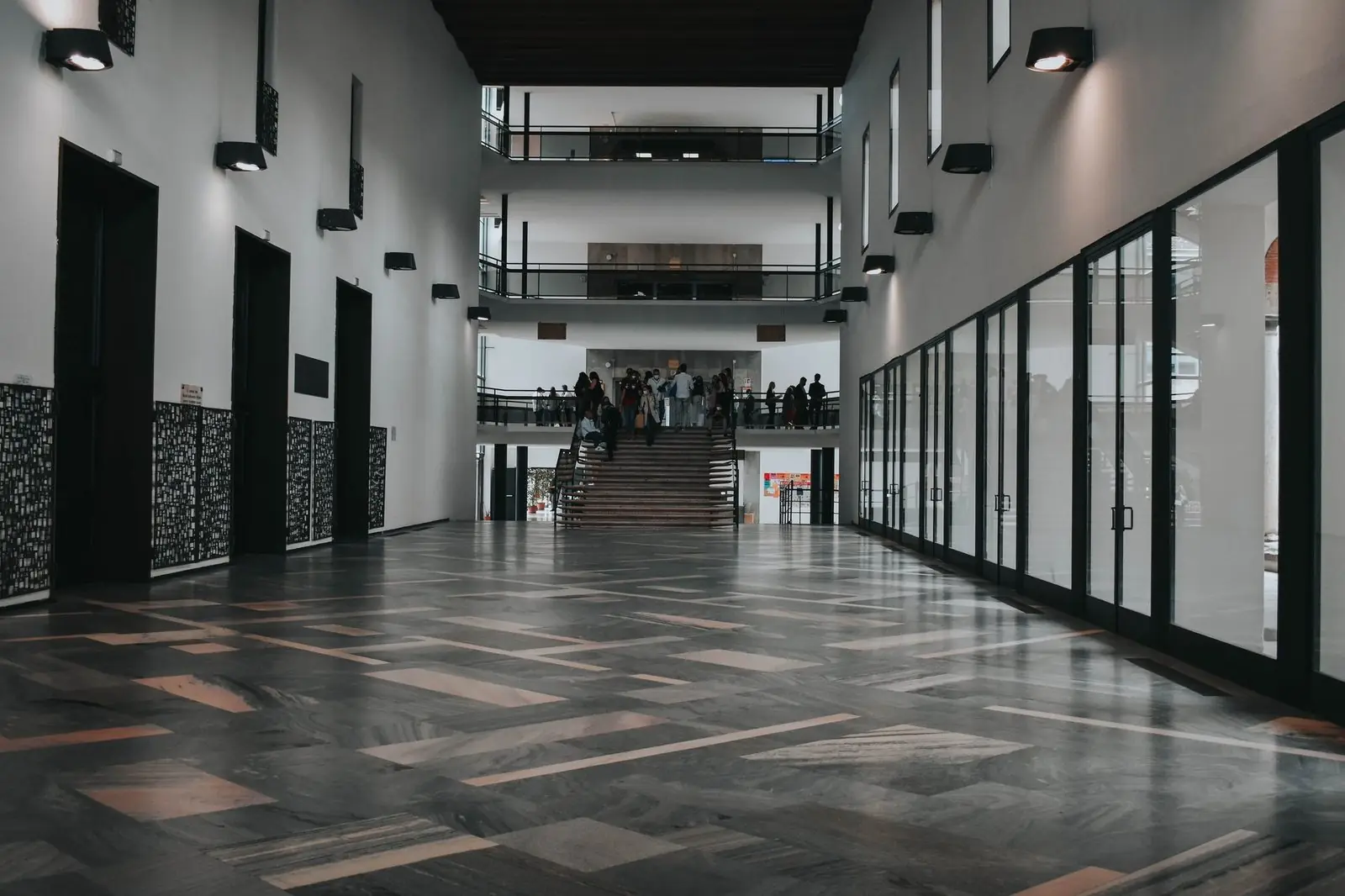 Wide indoor hall with a staircase and people on the upper level