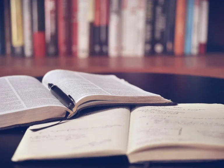 Two open books with handwritten notes and a pen on a desk